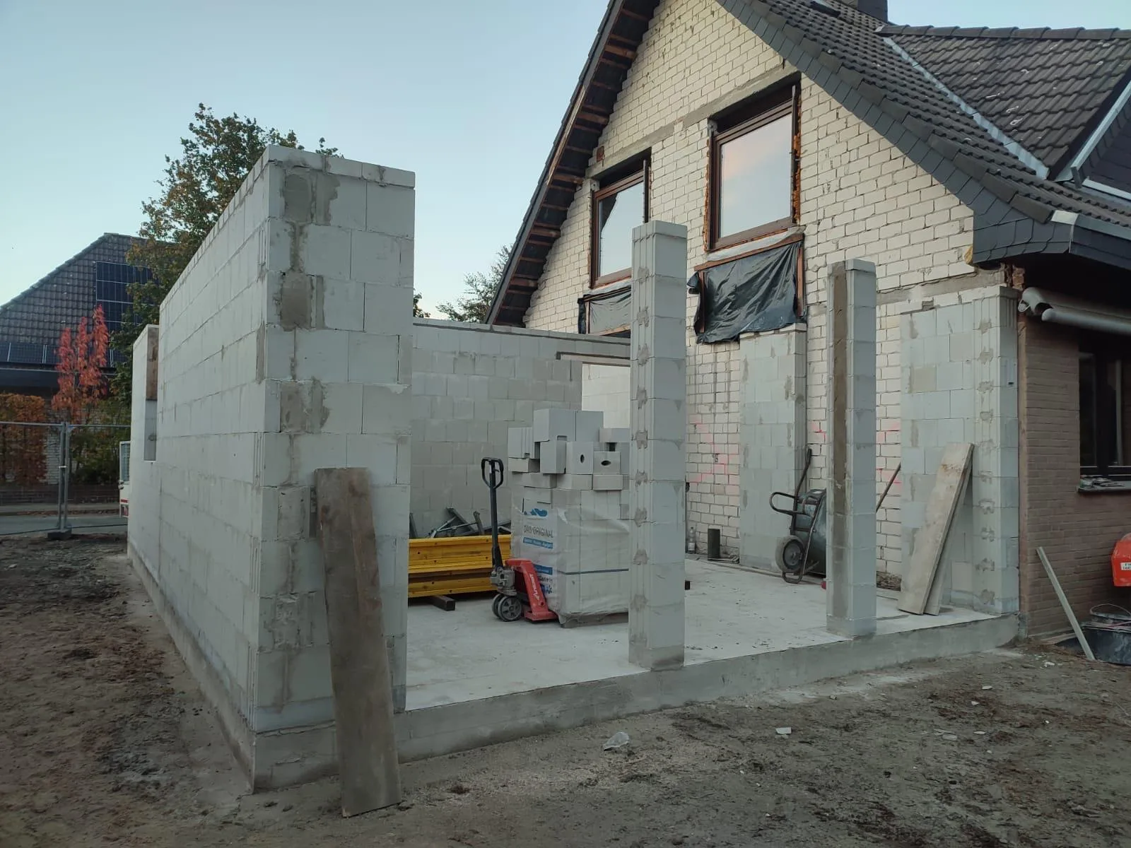 Rohbau eines Anbaus in Porenbeton mit Bodenplatte und Betonstützen in der Abenddämmerung